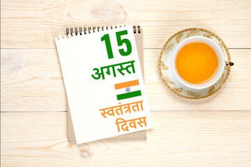 15 august indian independence day in hindi language, calendar paper sheet with tea cup on aged wooden table