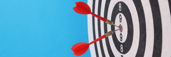 Game darts in center with darts on blue background.