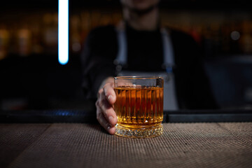 Barman holding out glass with alcoholic cocktail