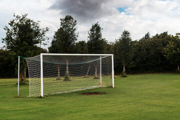 White soccer of football goal post on a grass field of a training ground.