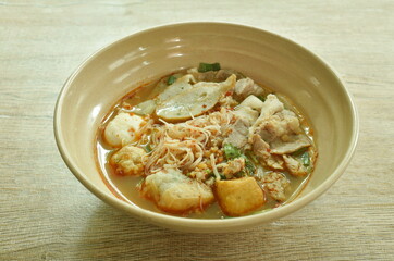 spicy vermicelli noodles topping slice boiled pork and ball in tom yum soup on bowl
