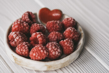 raspberries in a small ceramic bowl with a red heart decor
