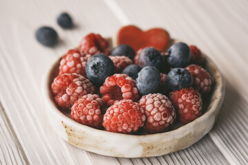 raspberries and blueberries in a small ceramic bowl