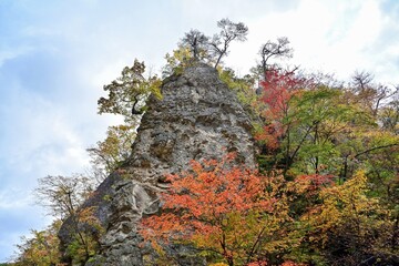 青空バックに見上げる巨大な岩と鳴子峡の紅葉のコラボ情景＠宮城