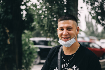 young man with fashion haircut , with a medical mask removed from his face and smiles. Close up portrait