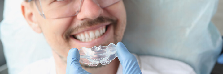 Dentist tries on transparent mouthguard to correct bite and bruxism problems