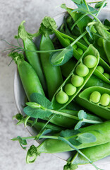 Fresh green peas pods and green peas with sprouts on concrete background.