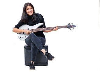 Portrait shot of a cute smiling young Thai-Turkish teenager playing the bass guitar while sitting...