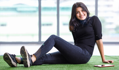 Portrait shot of a cute smiling young Thai-Turkish teenager with casual clothes sitting down on the...