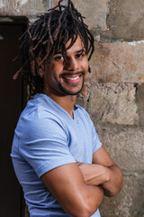vertical portrait of an attractive latin american man. He wears dreadlocks and looks at camera smiling