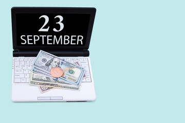 Laptop with the date of 23 september and cryptocurrency Bitcoin, dollars on a blue background. Buy or sell cryptocurrency. Stock market concept.