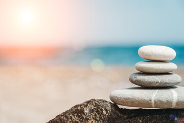 Zen stones are background. A pyramid of pebble stones against the background of the sky, sea and beach. Meditation, yoga, calming the mind and relaxation concept.