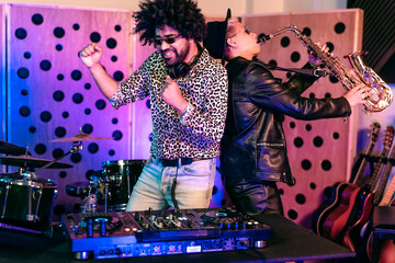 Young happy people playing music with dj mixer and saxophone in house studio - Youth musician...