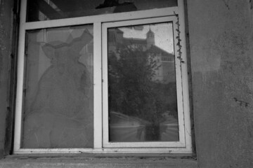 Old broken window in black and white color. One window pane is replaced with cardboard.