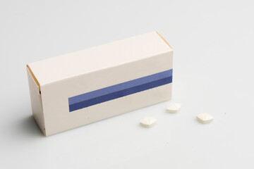 Blank pill box and some pills on white table