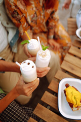 Iced milkshake. Young friends drinking milkshakes in a cafe. Summer refreshing drinks. Friendly lunch.