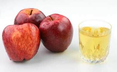 Apple Cider Vinegar in a glass cup with red apples in the background