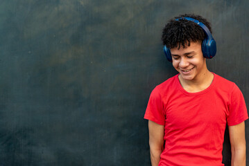Afro latin male teenager listening music against a wall