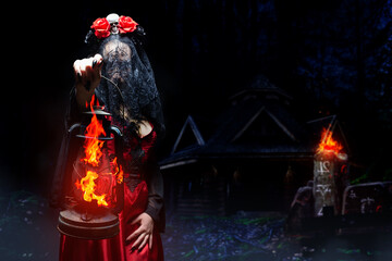 Sexy mysterious witch or sorceress in red gothic dress, black veil and crown with skull and roses...