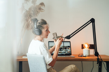 Woman radio host recording podcast at home studio. Female podcaster recording broadcasting into...
