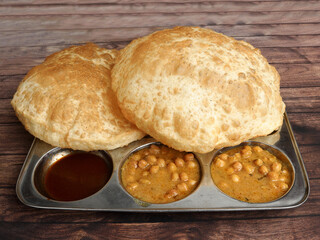 Chole Bhature, spicy Chick Peas curry also known as Chole or Channa Masala is traditional North Indian main course recipe and usually served with fried puri or Bhatura, selective focus