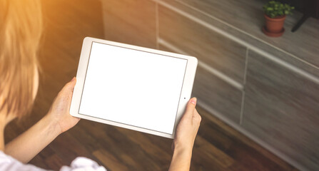 Mockup image of a woman holding digital tablet with blank white desktop screen with copy space in new apartment background