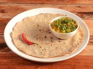 Zunka Bhakar Pithla or pitla, popular vegetarian recipe from India, served in rustic wooden background, selective focus