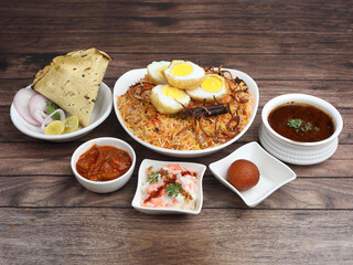 Egg Biryani Thali - Basmati rice cooked with masala roasted eggs and spices and served with mirchi ka salan,raita,sweet and papad. selective focus