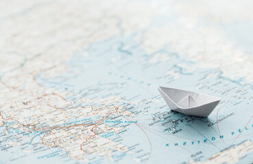 Travel concept - white paper boat on a map