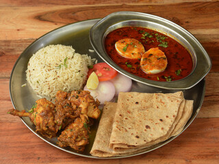 Chicken Thali from an indian cuisine, food platter consists Chicken fry,Boiled egg curry, lentils, jeera rice, and onions. selective