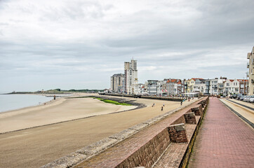 Fototapeta na wymiar Vlissingen, The Netherlands, July 25, 2021: view along the city's seafront with a sandy beach, an asphalt slope, a brick seawall and architecture in various styles
