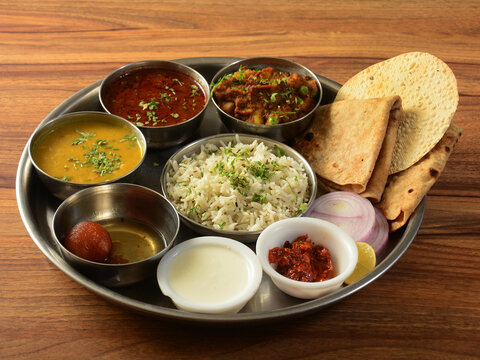 Maharashtraian Veg Thali from an indian cuisine, food platter consists variety of veggies, lentils, jeera rice, roti, sweet dish, curd, pickle etc., selective focus