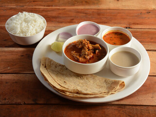 Chicken Thali from an indian cuisine, food platter consists of Chicken curry, steamed rice,lentils, roti and onions., selective focus