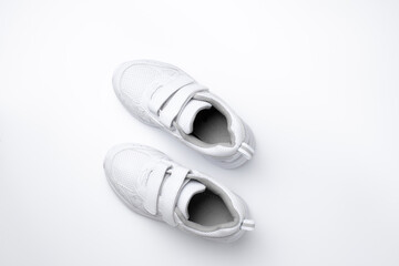 minimalistic flat lay for advertising of white kid sports shoes with velcro isolated on a white...