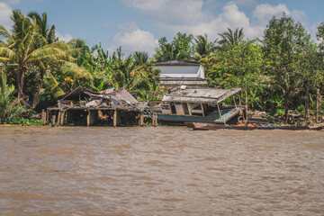 Fototapeta na wymiar Destroyed house on the river bank. Mekong River in Vietnam, South East Asia. Vung Tau, Vietnam