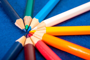 Many multicolored pencils on a blue felt background. Different colored pencils with space for text. Back to school. Art lessons.