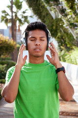 Young Latin American teenager with his eyes closed in concentration listening to the music on his headphones.