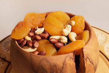 Fototapeta na wymiar Dried fruits and nuts peanuts and cashews in a handmade wooden plate. A healthy snack for everyone - nuts and dried fruits