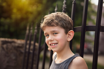 Obraz premium The little boy rests in the shade after a long walk during the hot summer weather, the boy smiles and shows his healthy permanent teeth that grow to replace the already bad baby teeth