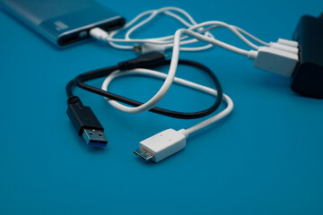 black and white USB in different type laid disorderly and mess on blue background , energy management and data transfer connector concept , selective focus on USB plug