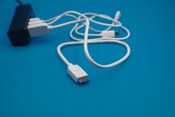 white USB in different type laid disorderly from USB hub and mess on blue background , energy management and data transfer connector concept , selective focus on USB plug