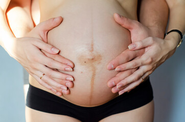 Male and female hands on a pregnant tummy
