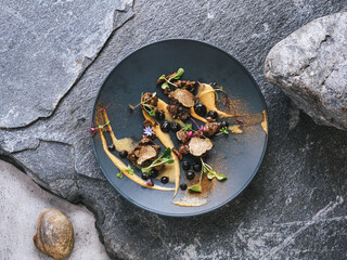 Experimental high gastronomy master piece from chef with black truffles decorated on the stone plate