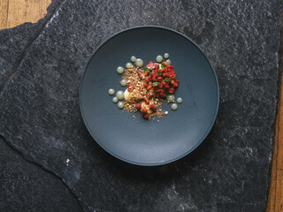 Exquisite restaurant dessert with red wild berries and flowers on the black 