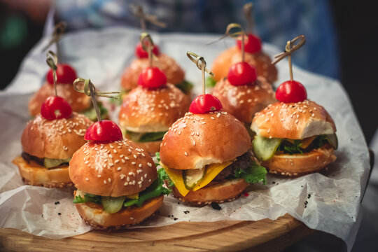 Burger mini burgers snacks on a wooden table with craft paper, beautifully decorated catering banquet table on corporate christmas birthday party event or wedding celebration