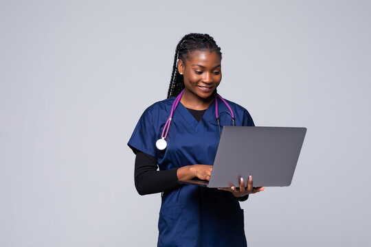 Beautiful African American woman doctor or nurse holding a laptop computer on a white background