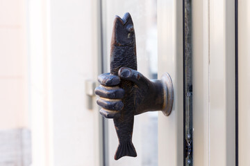 Hand-shaped doorknob with fish. Decorative element.