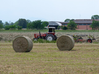 Bales of Hay in the Countryside and Tractor at Work in the background