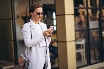 Young business woman in coat using phone