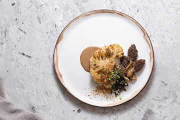 Cauliflower steak with morels on plate, restaurant dish, copy space - obrazy, fototapety, plakaty